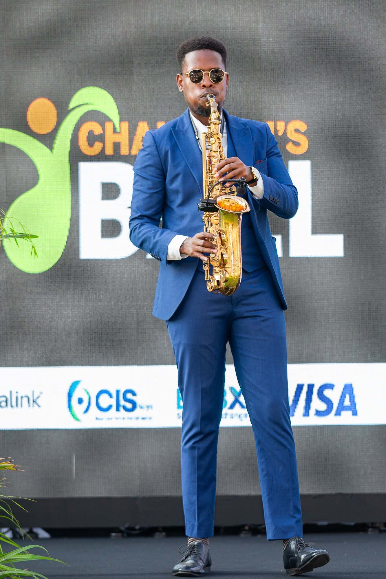 Ian in a blue suit performing on stage in front of the Chairman's Ball screen