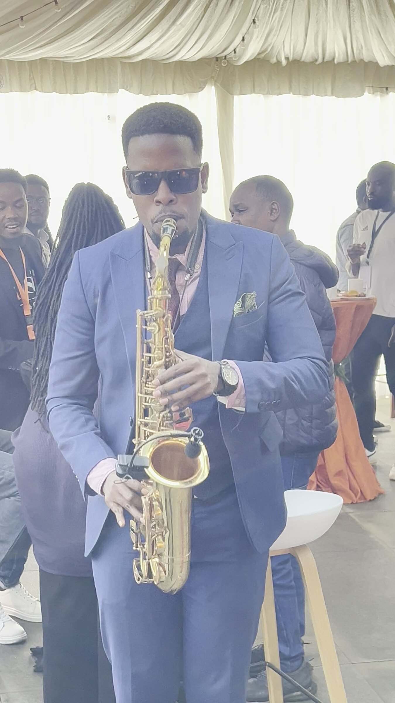Ian playing saxophone at arm’s length from guests at a daytime corporate event