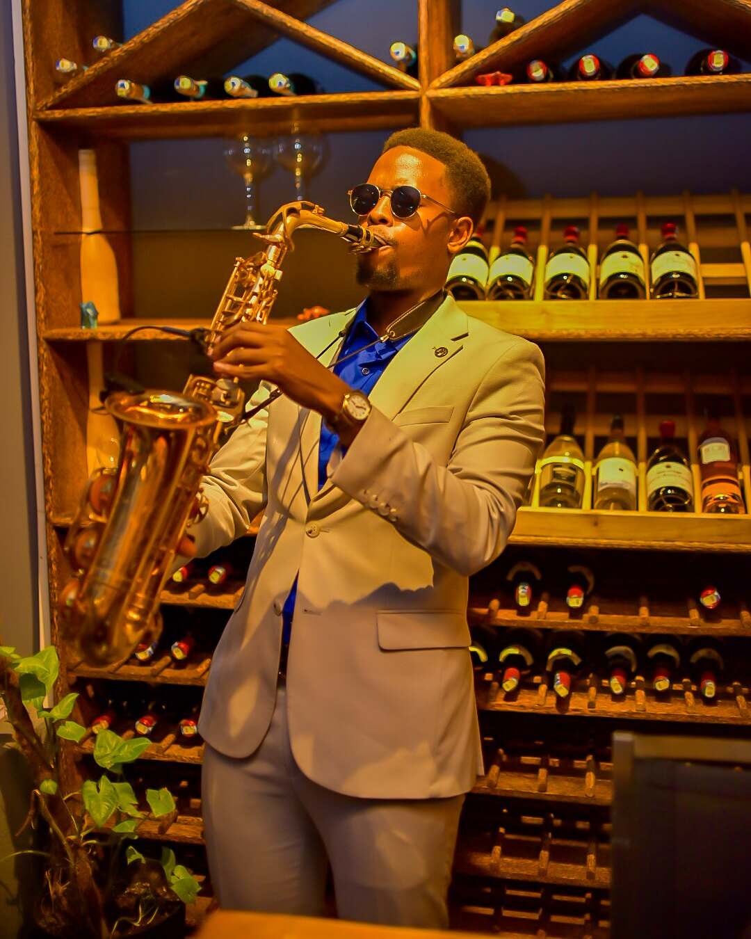 Ian playing saxophone in front of floor-to-ceiling wine racks at a private gathering